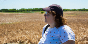 A photo of filmmaker Sarah Bulloch standing in front of a grassy field, looking to the left.